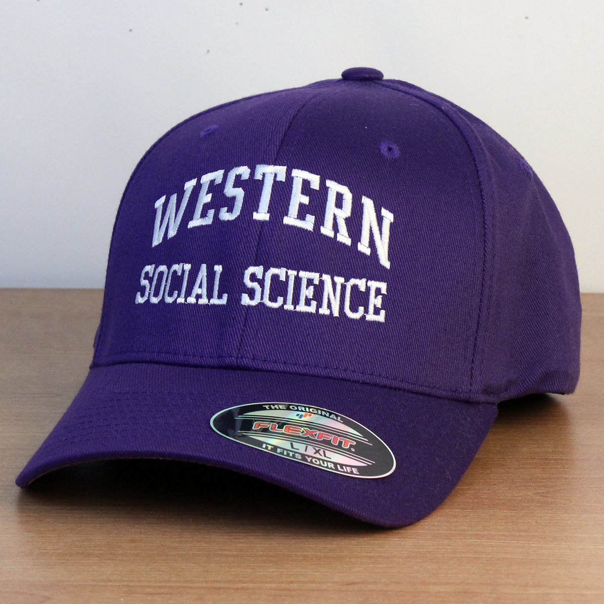 Purple ball cap with Western Social Science embroidered onto the front in white lettering. 