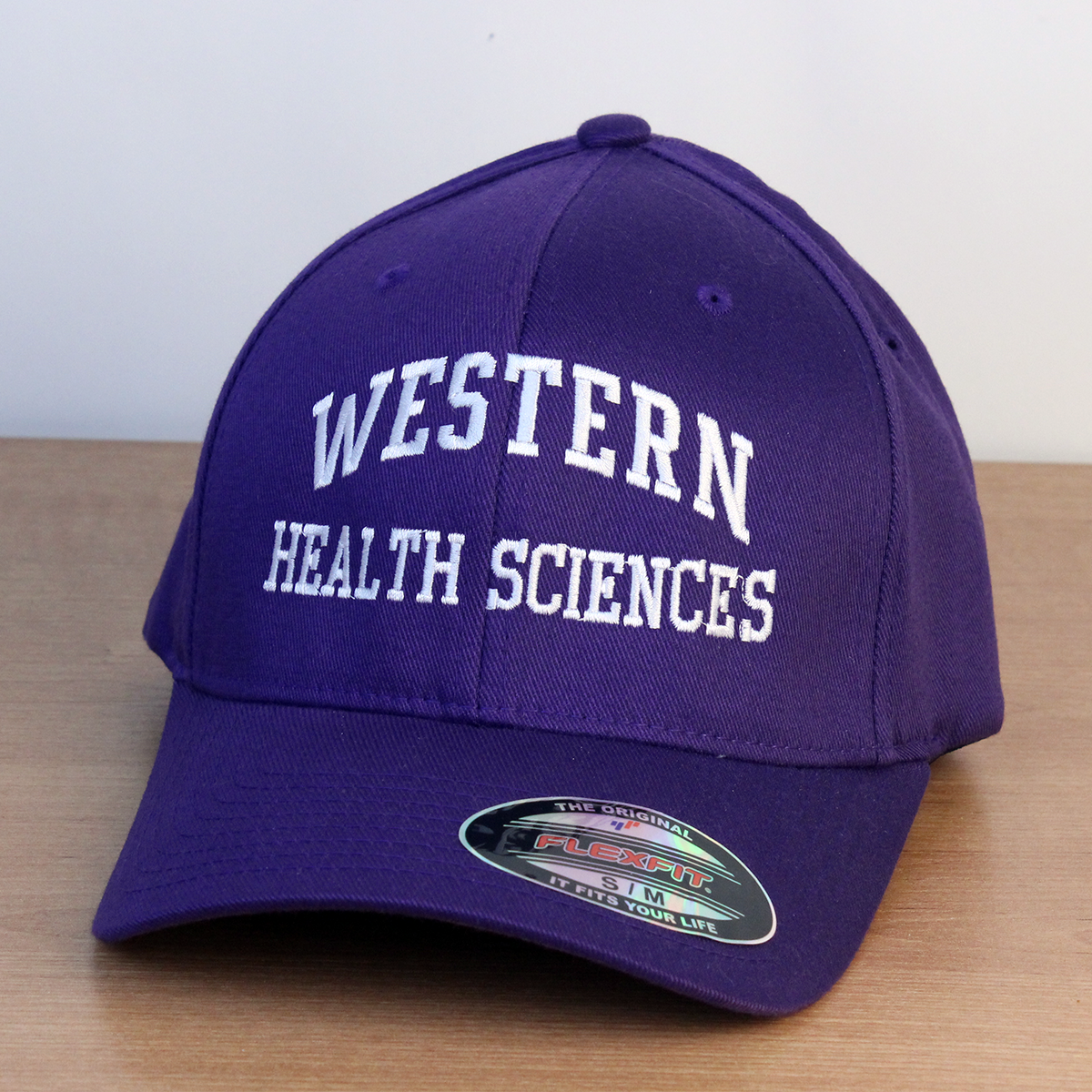 Purple ball cap with Western Health Sciences embroidered onto the front in white lettering.