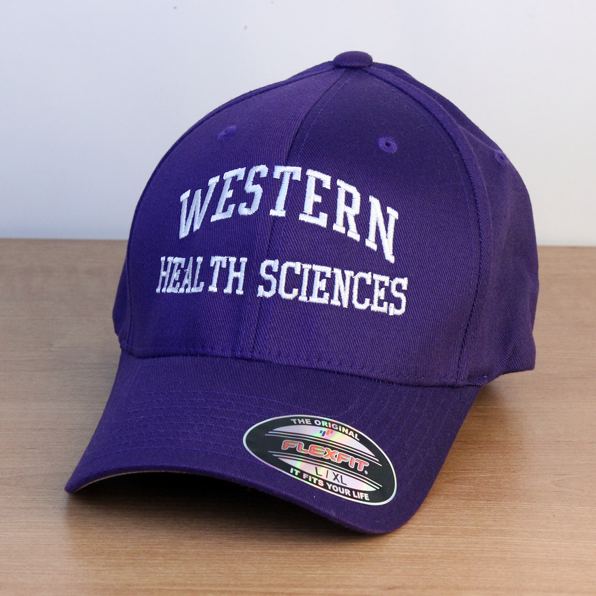 Purple ball cap with Western Health Sciences embroidered onto the front in white lettering.