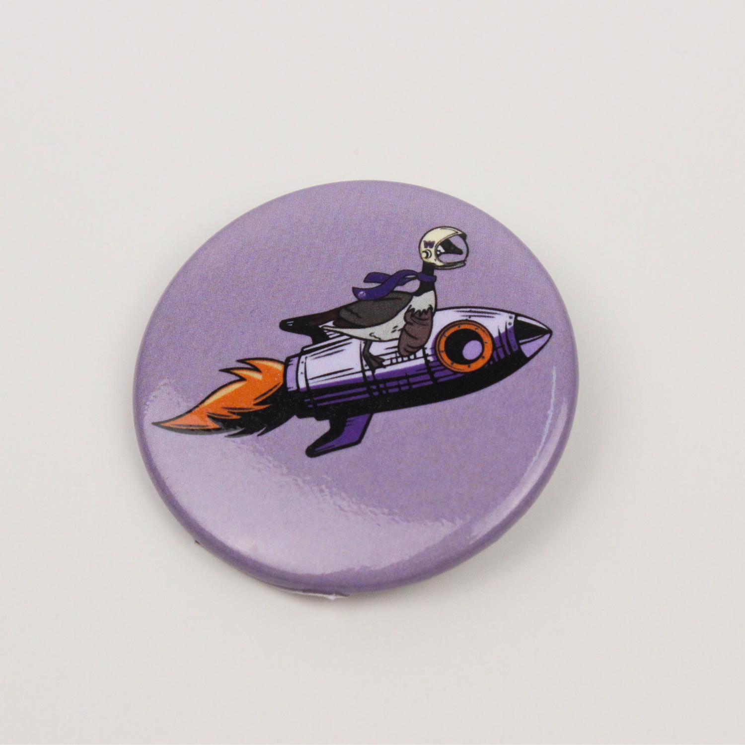 Drawing of Chase the Goose riding on a rocket ship on a round pin.