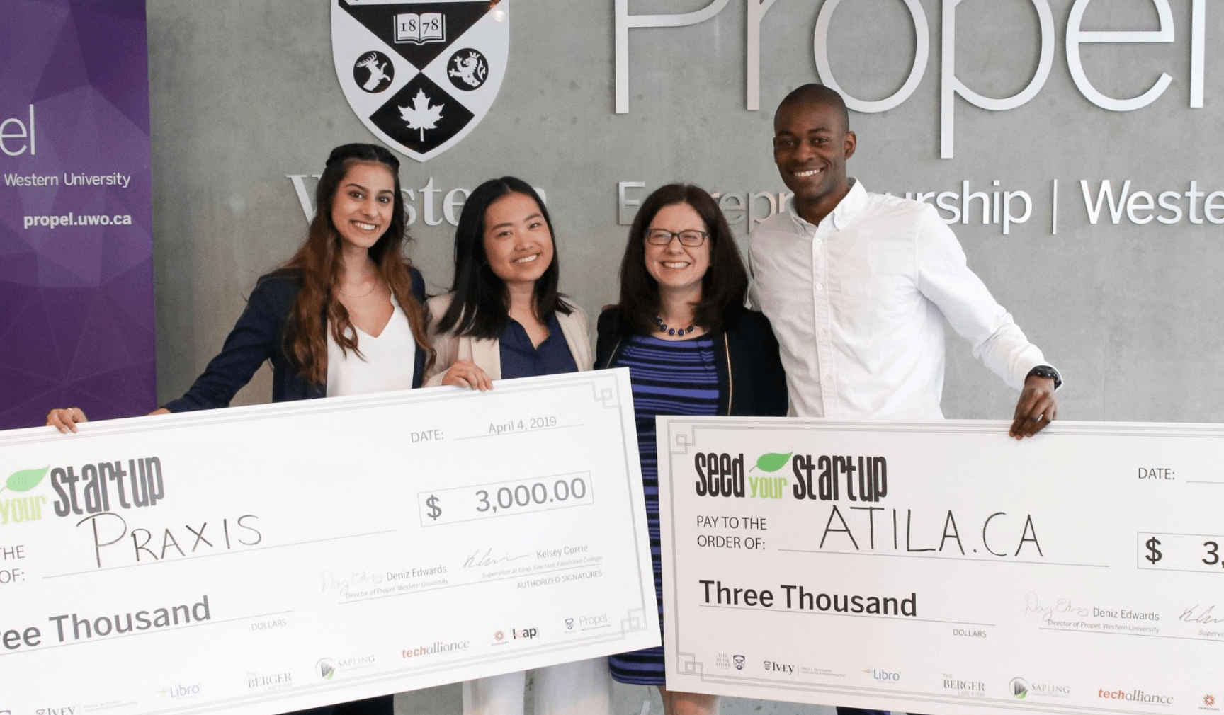 Four people holding up large cheques from Propel Seed Your Startup