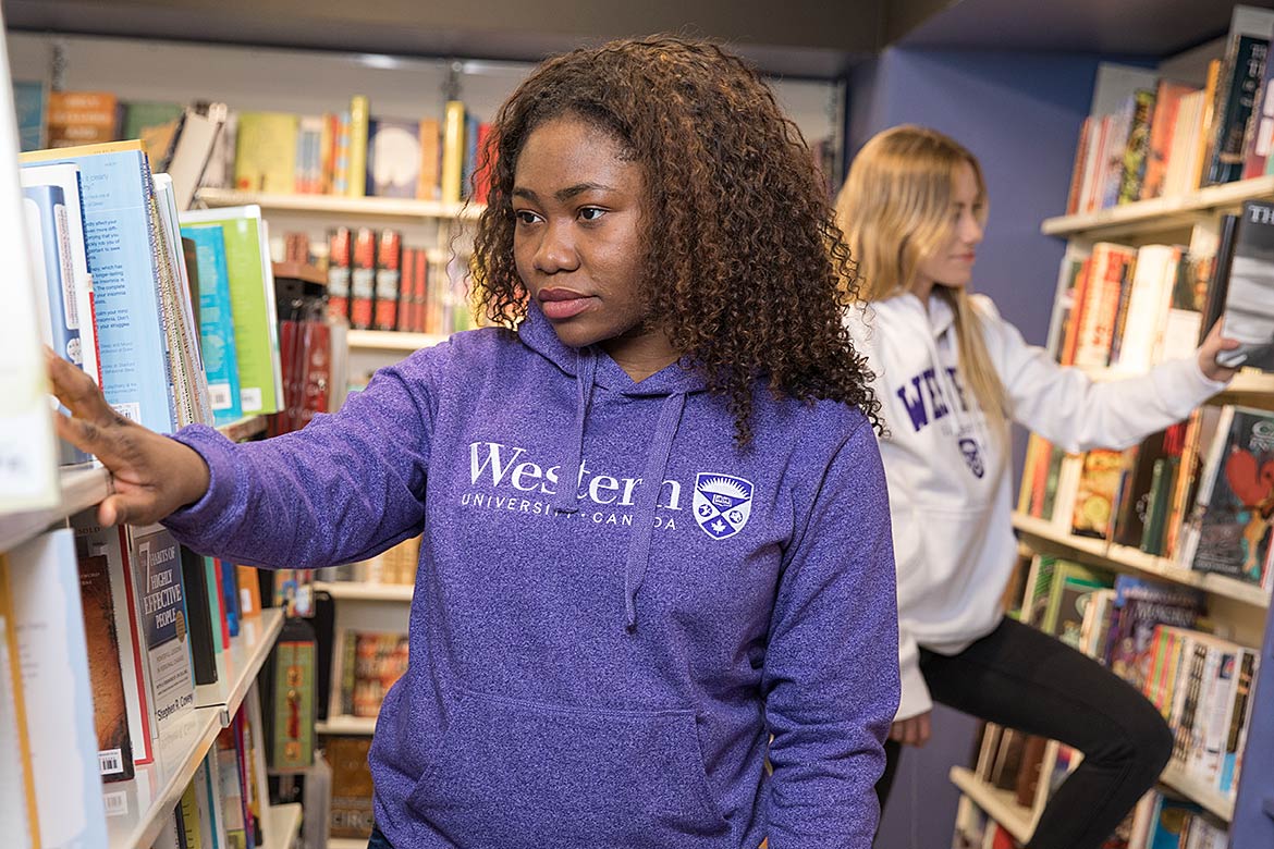 a student looking at a shelf of textbooks