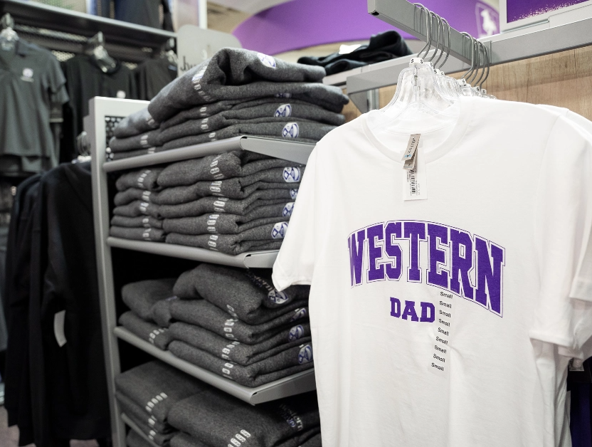 retail clothing rack with a white tshirt that says "Western Dad" in purple font