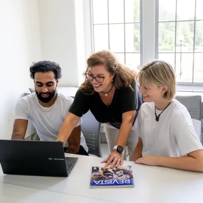 two students and their professor with textbook