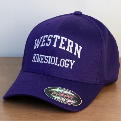 Purple ball cap with Western Kinesiology embroidered onto the front in white lettering.