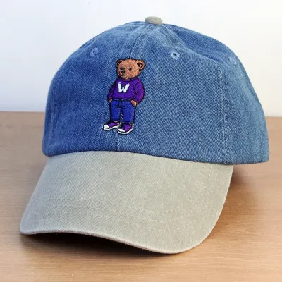 Denim and beige ball cap with embroidered brown teddy bear wearing a purple "W" sweater.