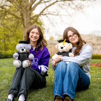 Girls sitting on hill holding Graduation Bear Plushies