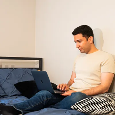 Student sitting on their bed on their laptop