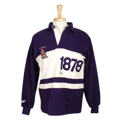 Vintage rugby shirt with white and purple stripes, a buttoned collar and cuffed sleeves. "Est. 1878" appliqued on the left side. The vintage coat of arms is embroidered on the right chest. 