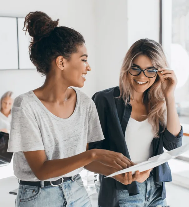 Two women laughing while looking at a document