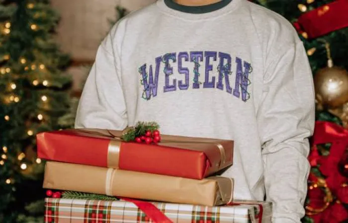 Student holding presents in Western crewneck