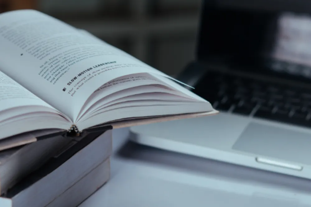 Stack of textbooks in front of a laptop